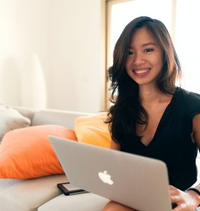 Uśmiechnięta kobieta siedząca z laptopem na kanapie
