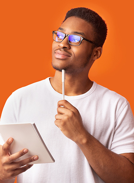young man in glasses thinking with a notebook and pen in his hands